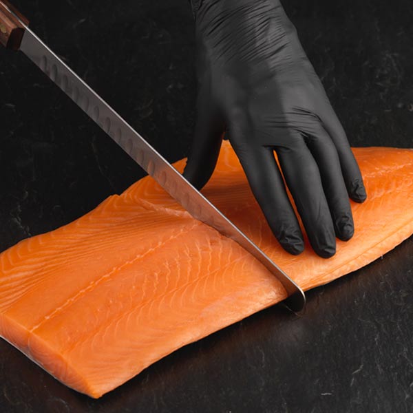 Filet knife cutting side of smoked salmon